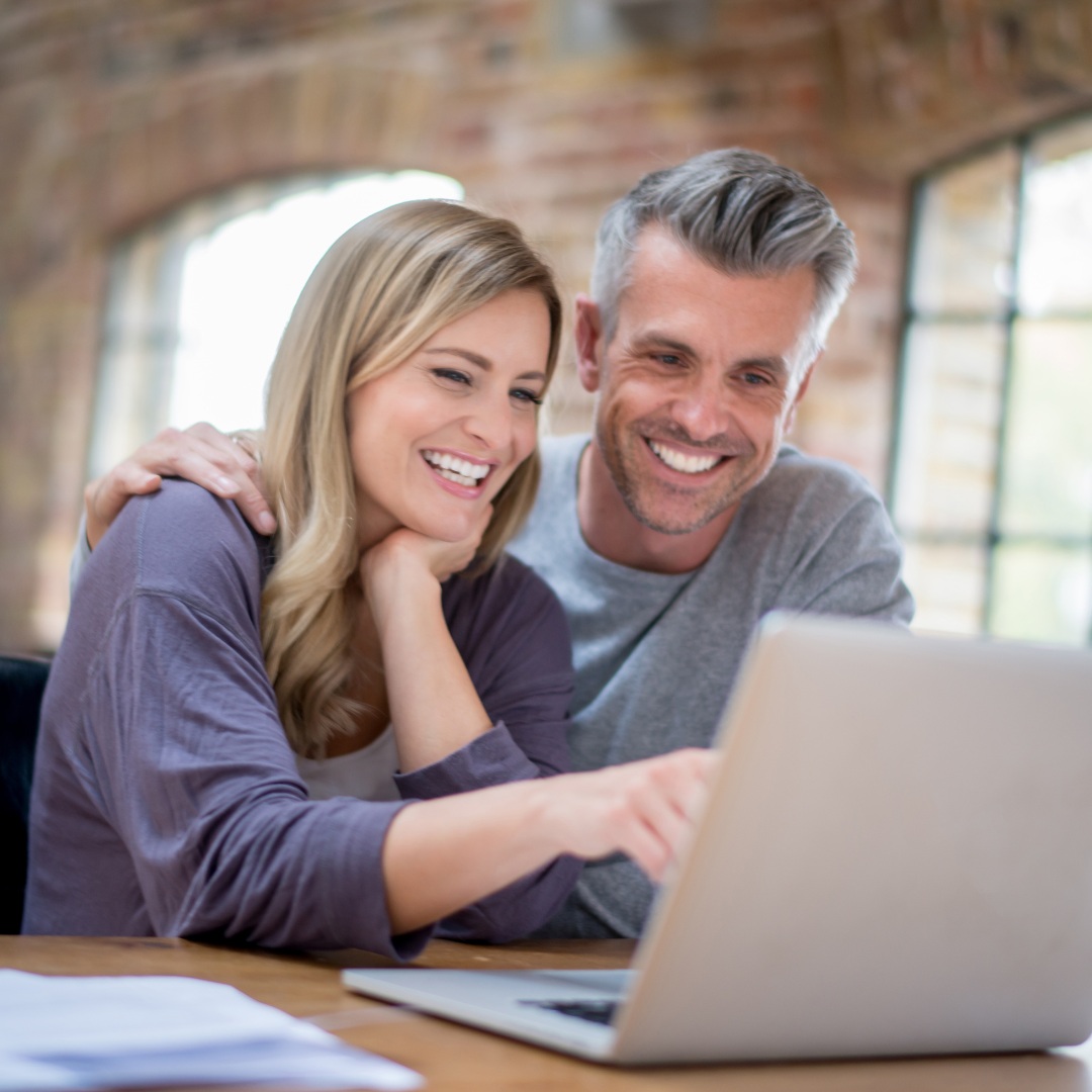Couple using a laptop together for real estate and loan package services